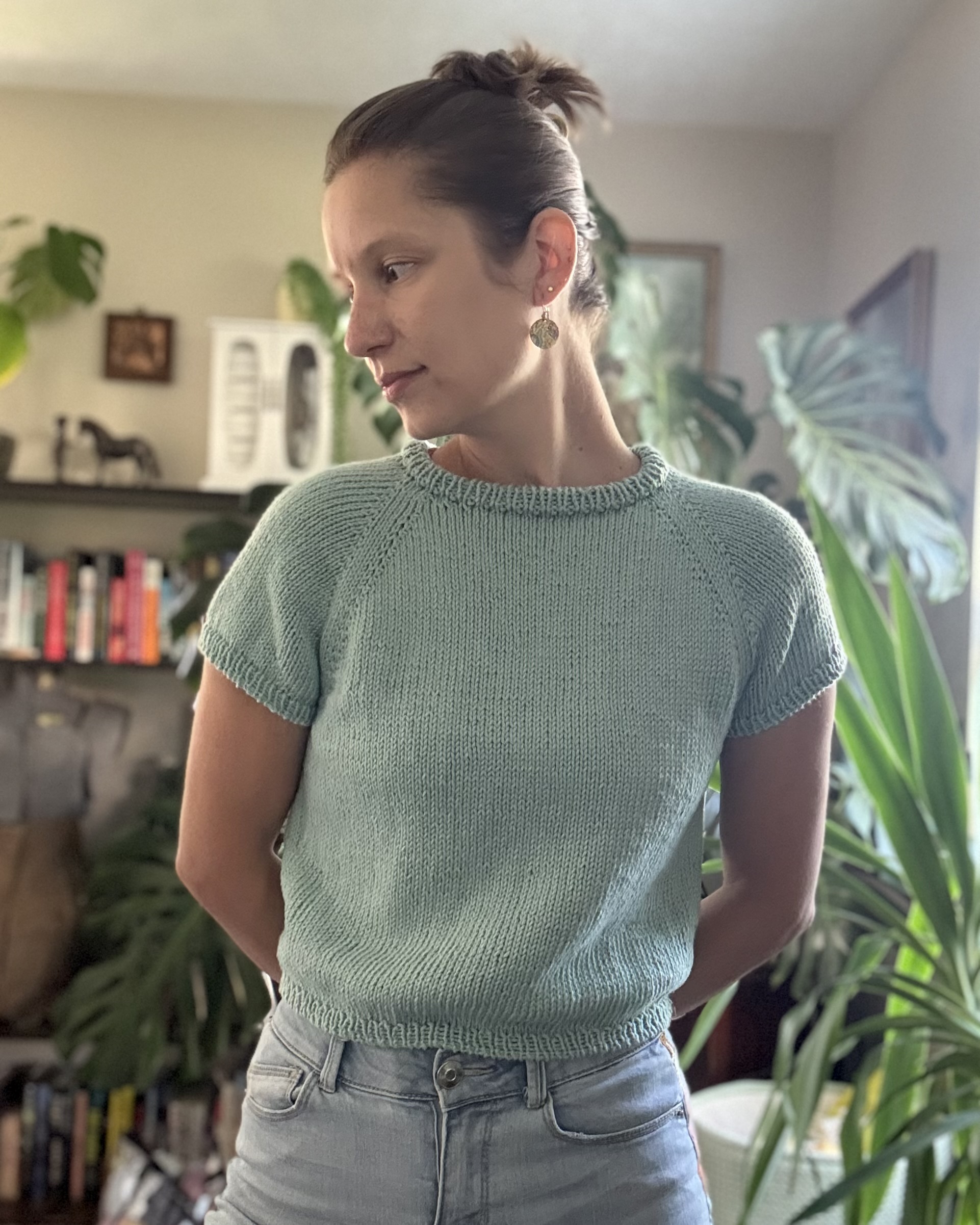 Laramie is wearing a hand knit tee shirt. The shirt is teal with short sleeves and a raglan construction. The body is slightly cropped.